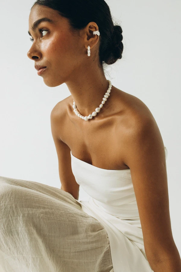 Modelka w białej stylizacji prezentuje nausznicę BOND silver – srebrny ear cuff z teksturą inspirowaną naturą. Modelka w białej stylizacji prezentuje nausznicę BOND silver – srebrny ear cuff z teksturą inspirowaną naturą.
