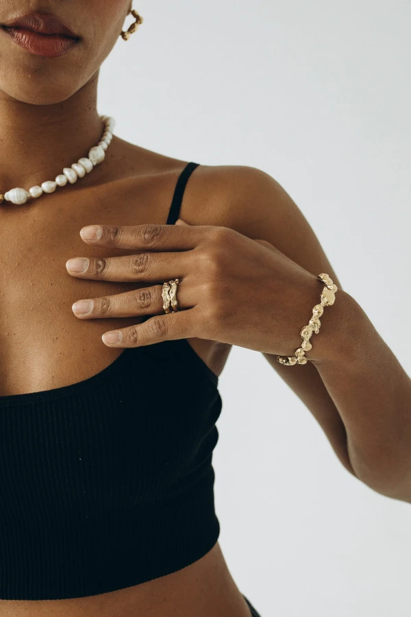 Kobieta w czarnym topie nosi złotą bransoletę BOND GOLD – modna, designerska biżuteria premium.